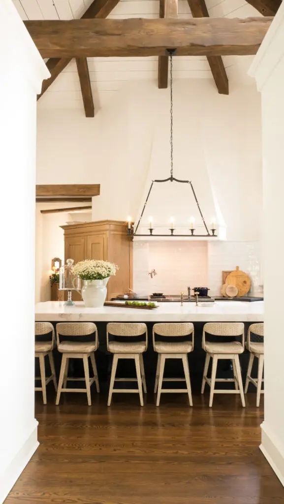 Luxury Hamptons kitchen design with vaulted ceilings, rustic wood beams, and marble island”