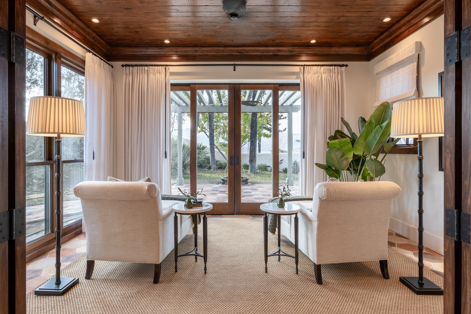 Luxury interior design sunroom with clay tile, dark wood details, and French doors to outdoor space