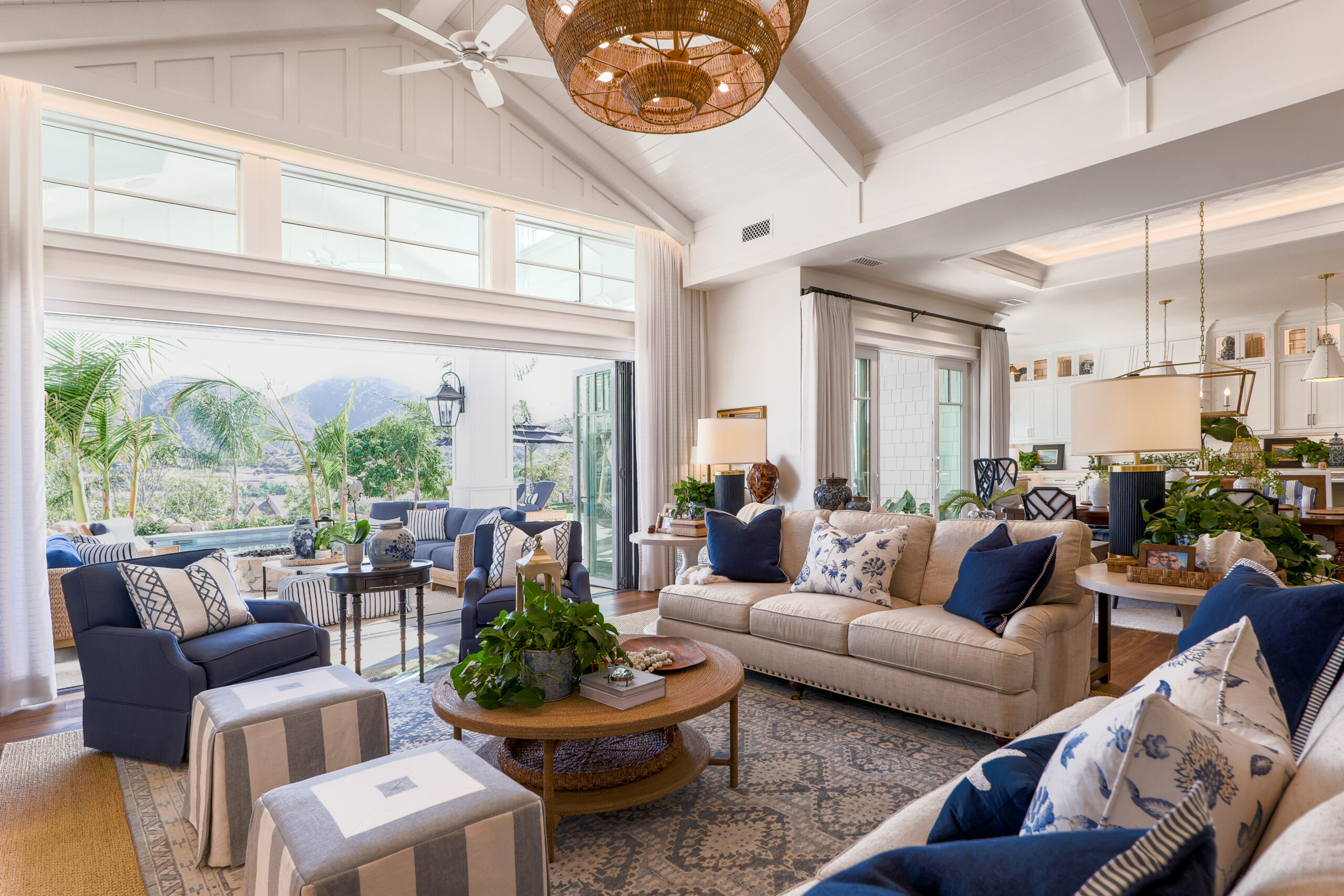 Luxury interior design living room with blue and white palette, mountain view, and palm trees