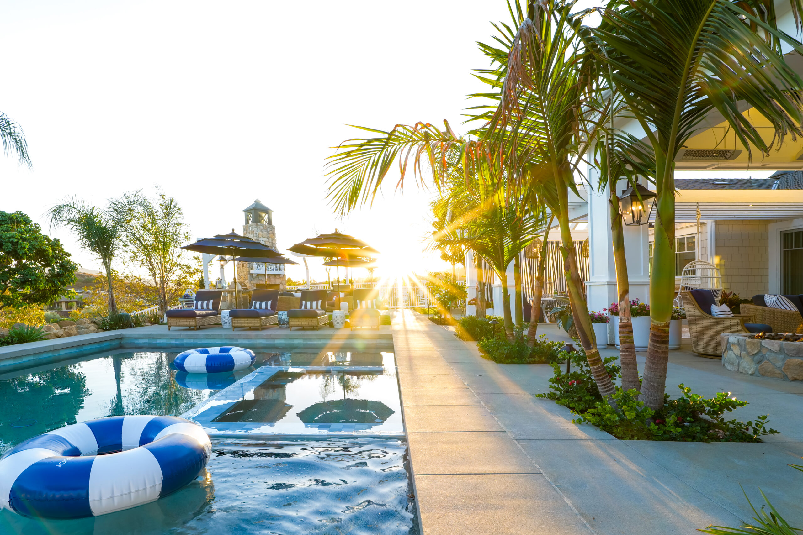 Luxury pool with navy blue accents and palm trees at golden hour in tropical setting