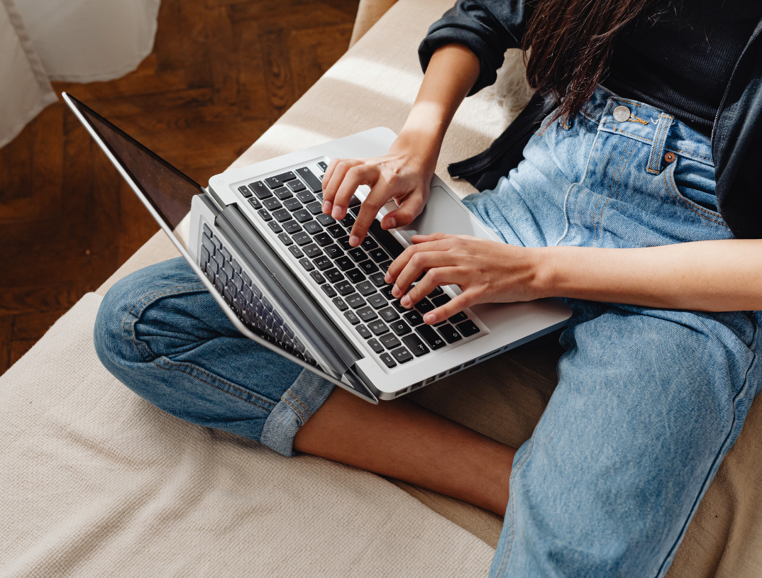 Digital marketing content creator using laptop on couch in home interior